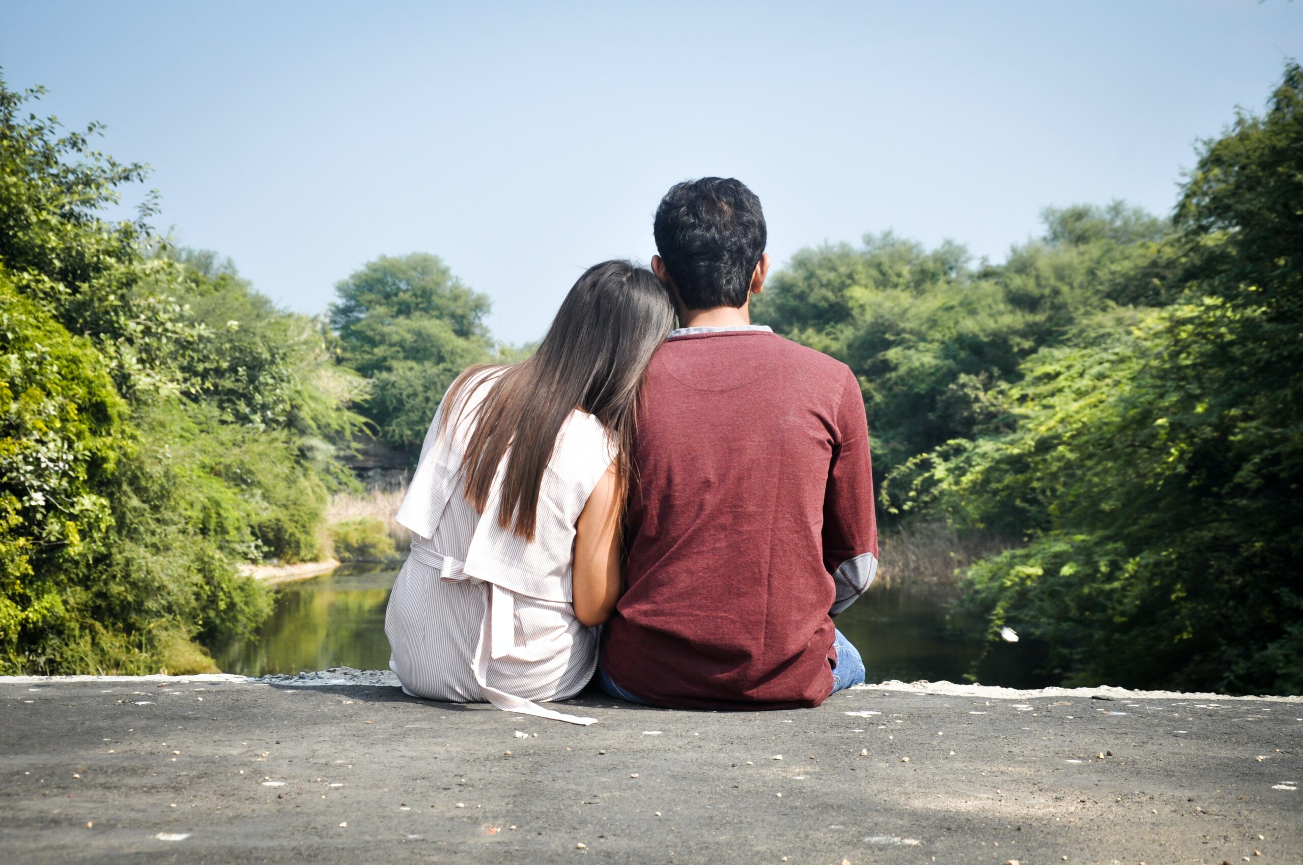 A couple sitting on a bridge's edge, enjoying a peaceful moment together. 1