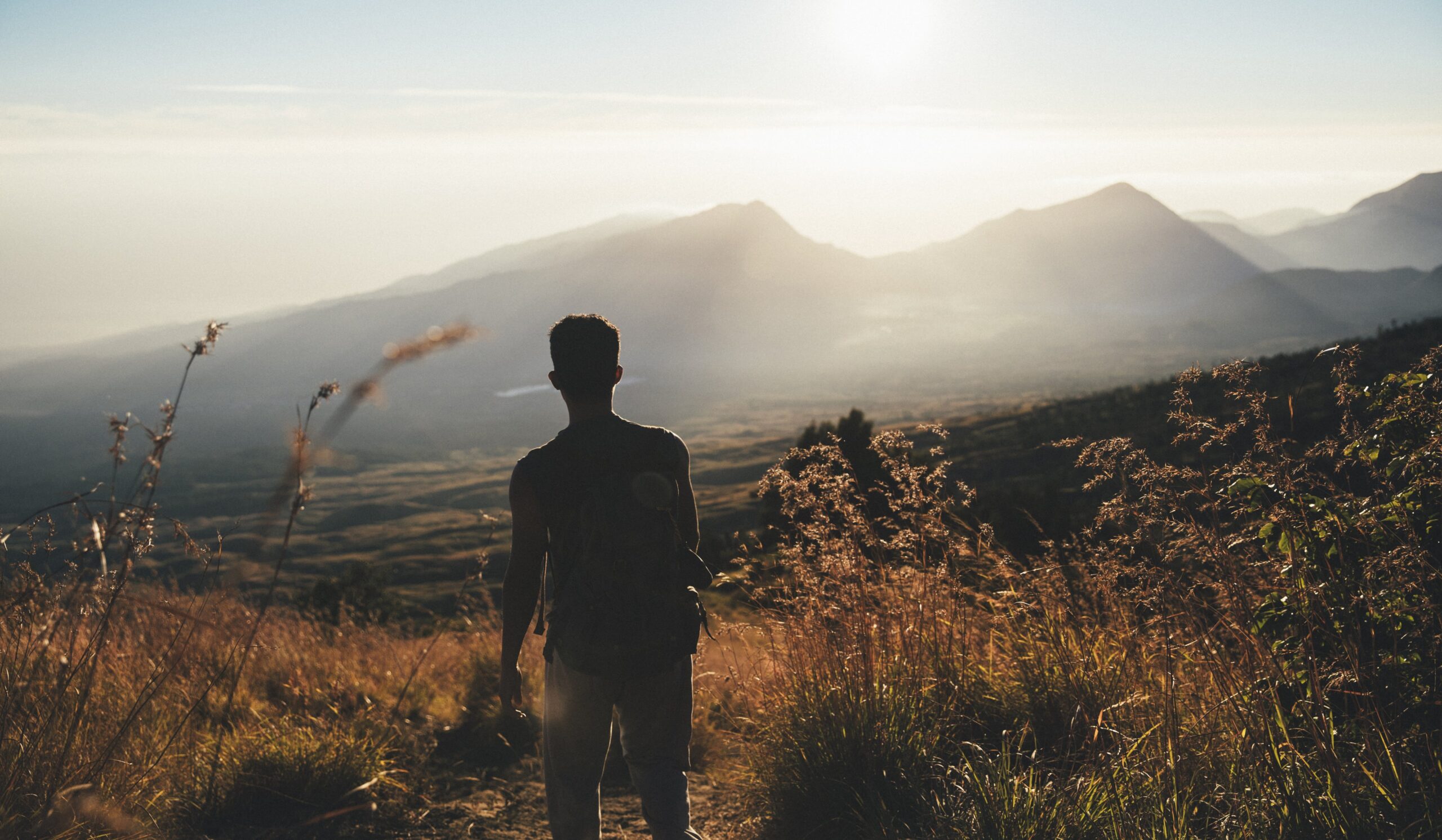 A man on a mountain peak, enjoying a vibrant sky.